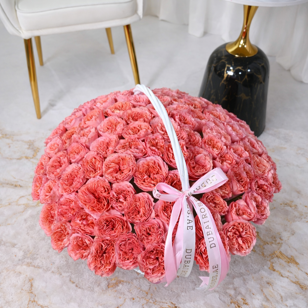 Large bouquet of pink expression roses wrapped with a pink ribbon on a marble surface.