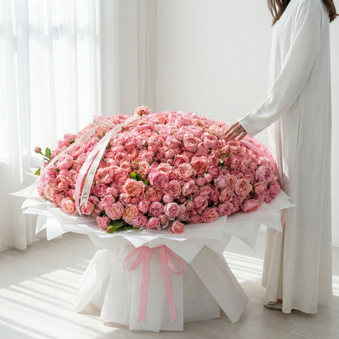 Front view of a giant Pink Julietta rose bouquet with crisp white gift wrapping and long decorative pink silk ribbons.