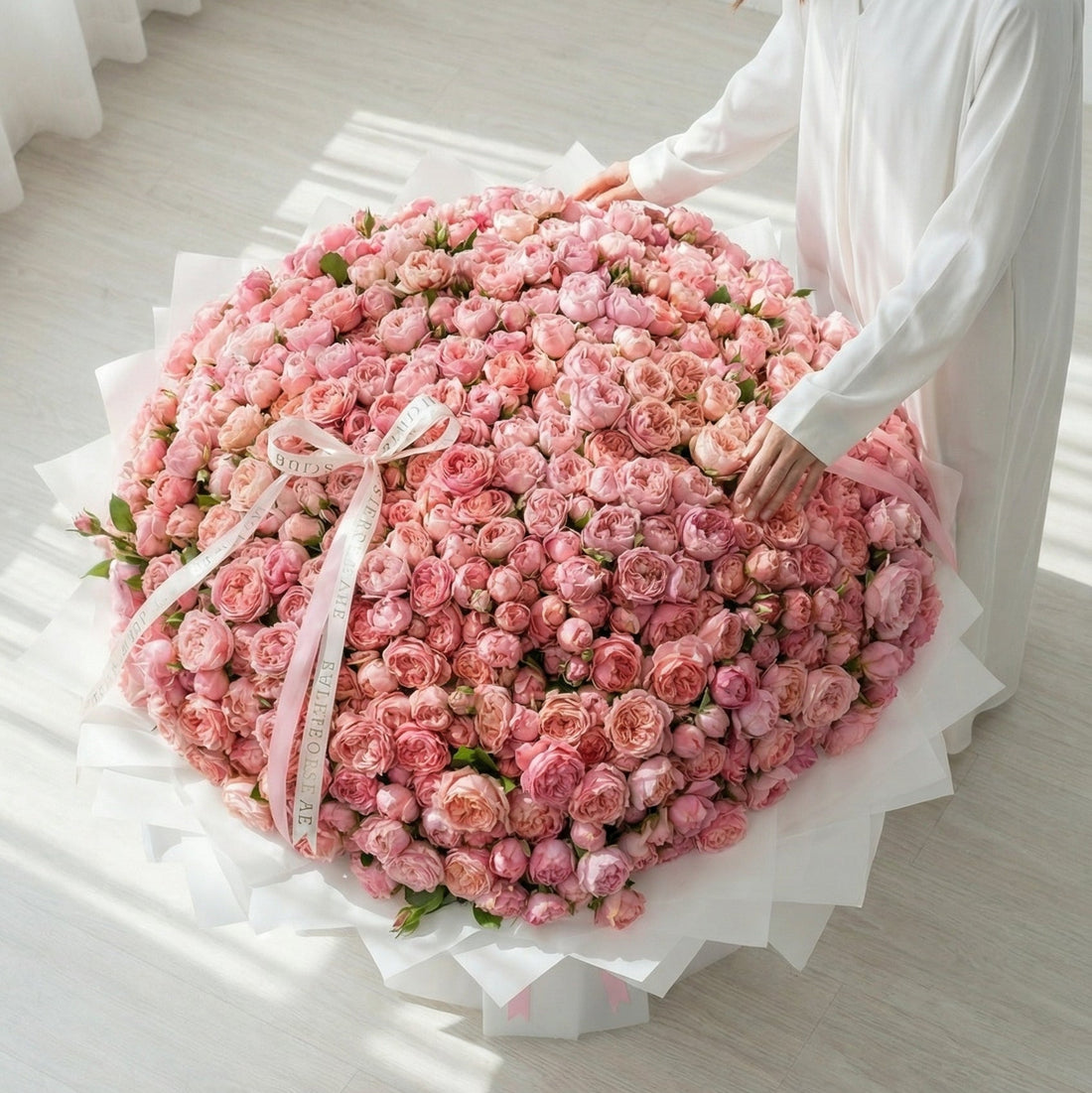 Front view of a giant Pink Julietta rose bouquet with crisp white gift wrapping and long decorative pink silk ribbons.