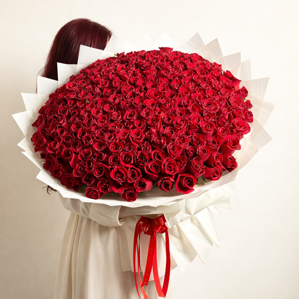 A massive, grand-scale luxury bouquet featuring 300 fresh red roses wrapped in premium white pleated paper and finished with signature red silk ribbons.
