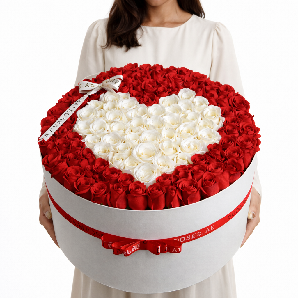 a woman holding a white round box of red roses with heart shape of white roses in middle of the arrangement.