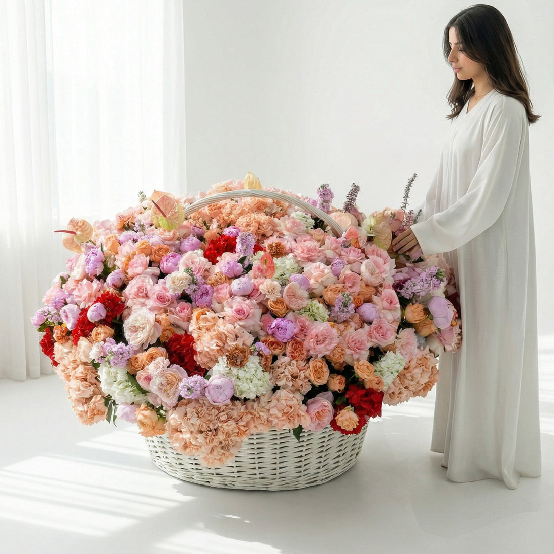 Woman holding a large basket filled with colorful flowers in a bright room.