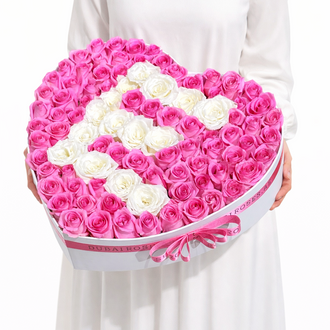 Close-up of a personalized heart-shaped rose box with a white rose initial "E" surrounded by a sea of pink roses and finished with a pink ribbon.