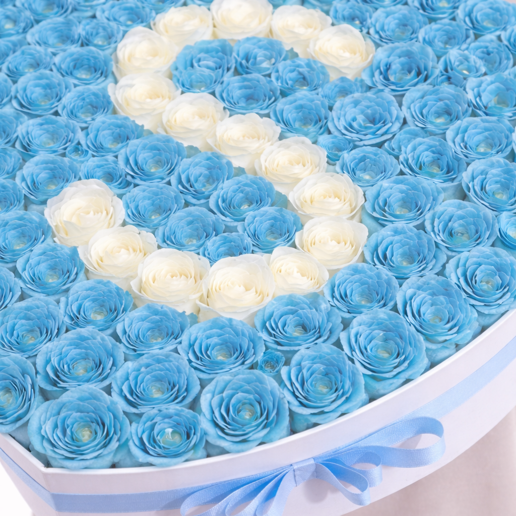 a close up photo of blue roses in heart box with letter S