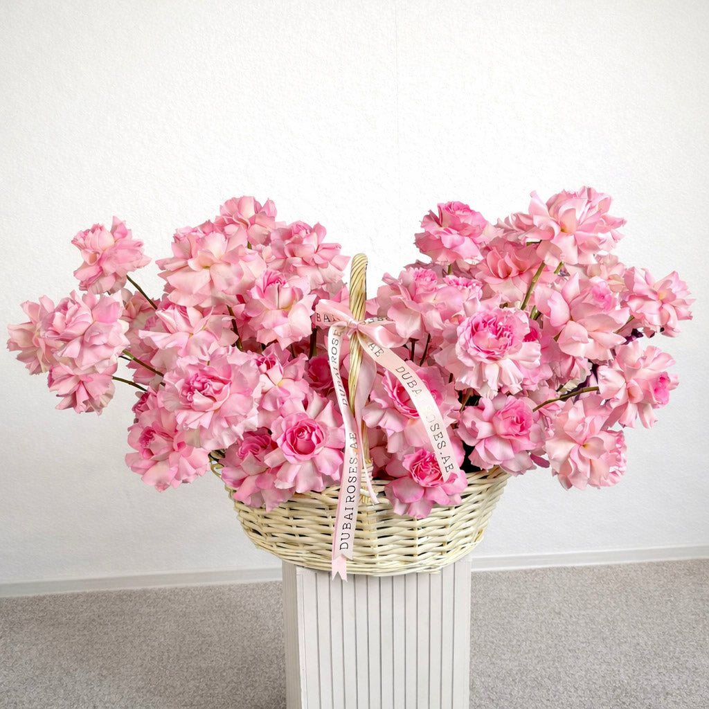 Basket of pink flowers on a white surface with a light gray background