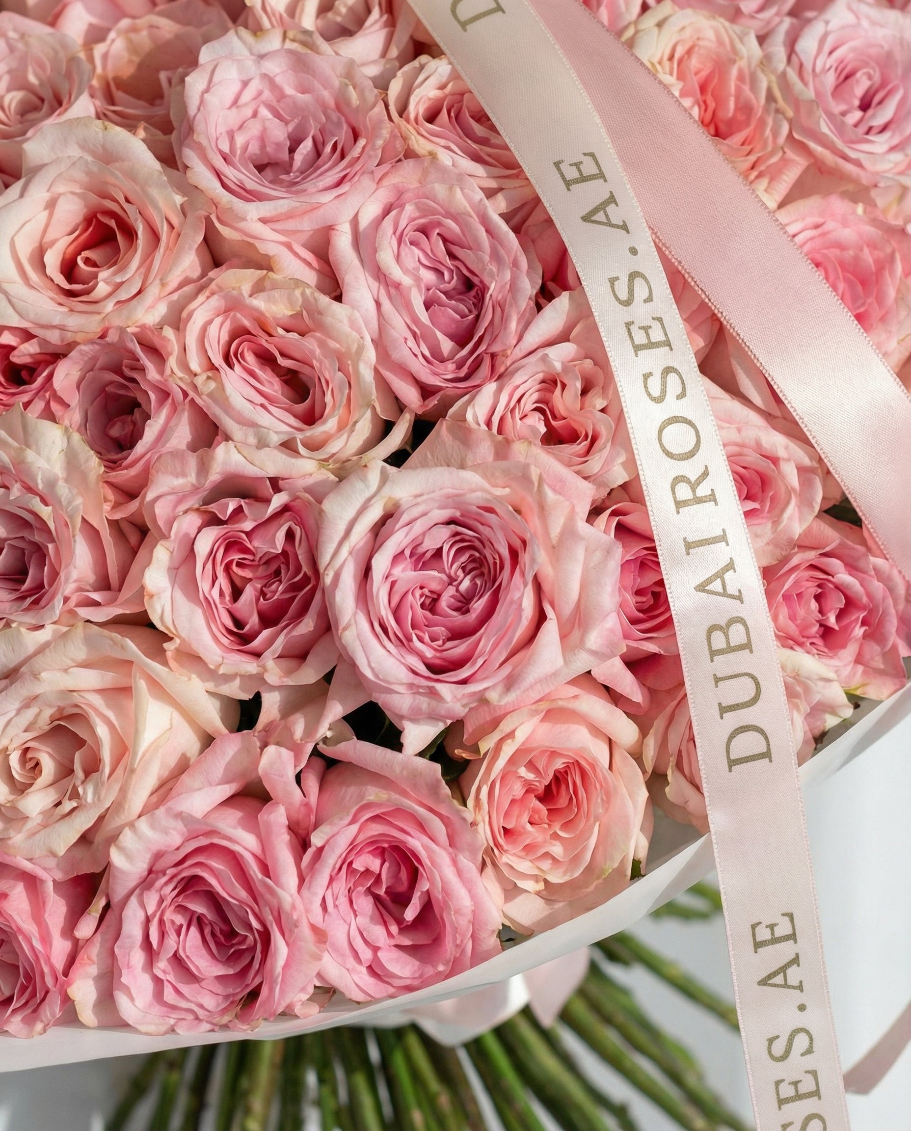 Box of pink roses with a visible 'Dubai Roses' ribbon.