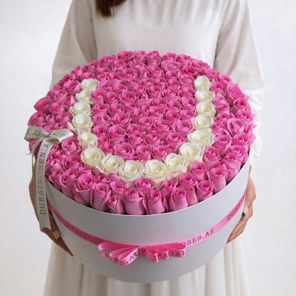 Large white round luxury flower box filled with dense pink roses and a custom letter "U" crafted from fresh white roses.