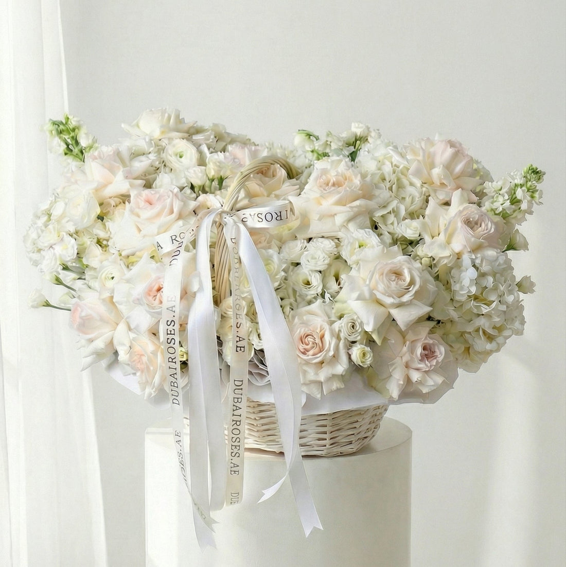 Bouquet of white flowers in a basket on a white pedestal with a white background
