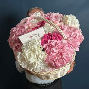 A Small basket of white and pink hydrangeas with some dark pink julieta roses